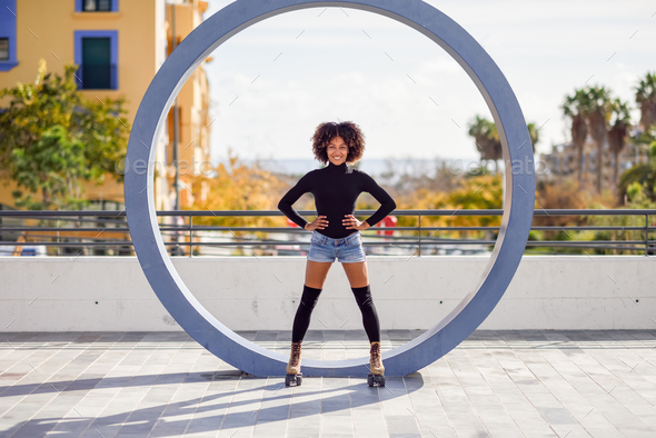Black woman on roller skates riding outdoors on urban street - Stock Photo - Images