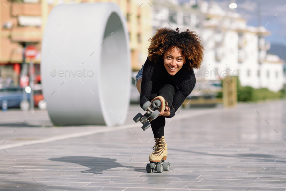 Black woman on roller skates riding outdoors on urban street - Stock Photo - Images