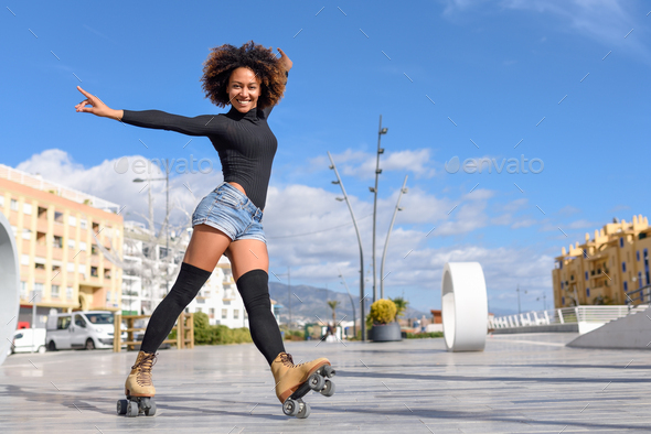 Black woman on roller skates riding outdoors on urban street - Stock Photo - Images