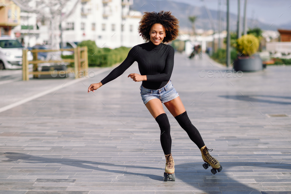 Black woman on roller skates riding outdoors on urban street - Stock Photo - Images