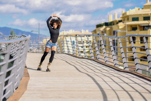 Afro hairstyle woman on roller skates riding outdoors on urban b - Stock Photo - Images