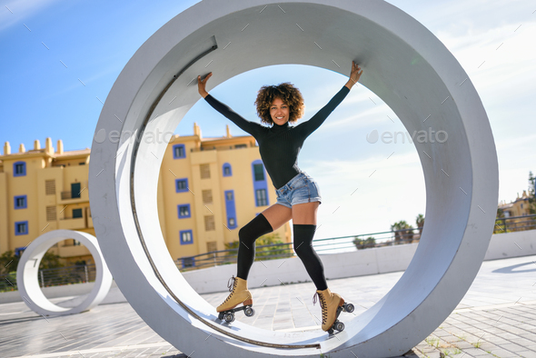 Black woman on roller skates riding outdoors on urban street - Stock Photo - Images