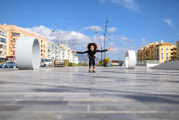 Black woman on roller skates riding outdoors on urban street - Stock Photo - Images