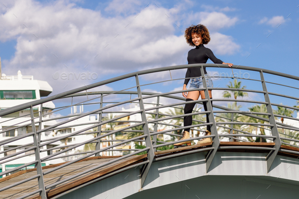Afro hairstyle woman on roller skates riding outdoors on urban b - Stock Photo - Images