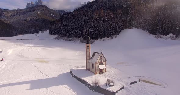 AERIAL: Church with snow in Dolomites in Italy alt