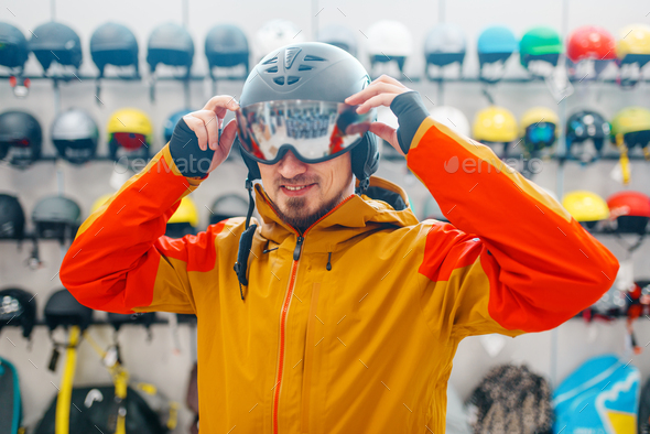 Man trying on helmet for ski or snowboarding - Stock Photo - Images
