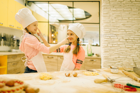 Two smiling little girls cooks in caps having fun