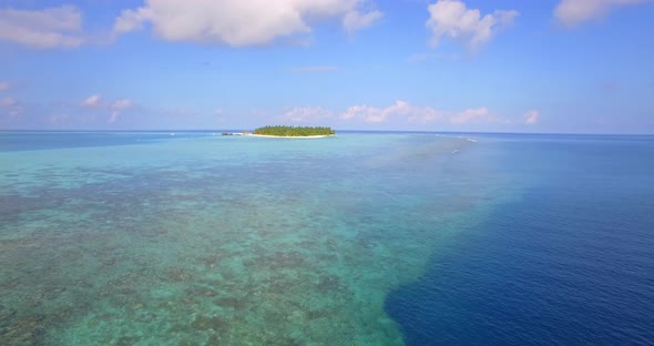 Aerial drone view of a man and woman couple snorkeling over the coral reef of a tropical island alt