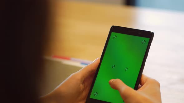 Close up young Asian woman using smartphone with green screen at office.