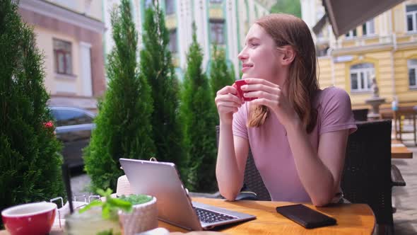 Young Woman Talking on the Phone in a Cafe on a Summer Terrace alt
