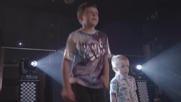 Two Young Boys Dance and Party at a Children's Disco with Bright White Lights Behind Them - Ungraded alt