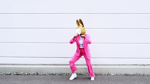 Businesswoman wearing donkey mask dancing in front of white wall