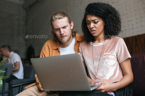 Upset boy and girl sitting in restaurant with laptop in hands - Stock Photo - Images
