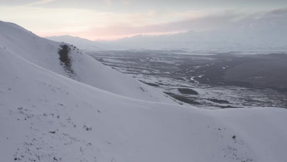 Breathtaking Aerial View of White Snow on Black Mountain Rocks at Sunset alt