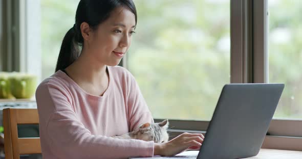 Woman work on laptop computer with her cat at home alt