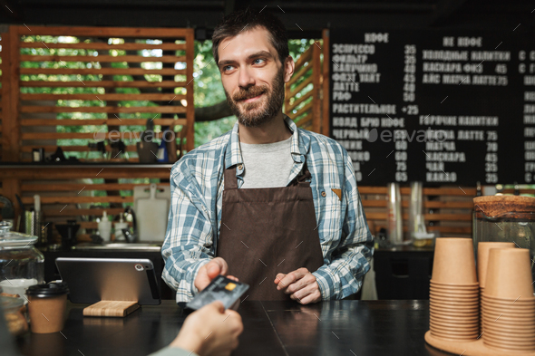 Portrait of happy barista man taking credit card from customer w - Stock Photo - Images