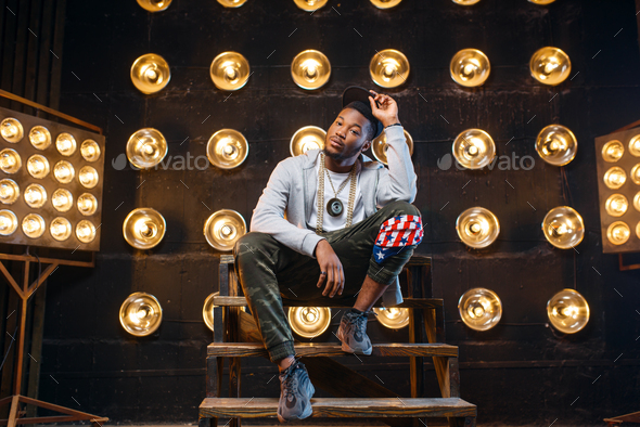 Black rapper in cap poses, perfomance on stage - Stock Photo - Images