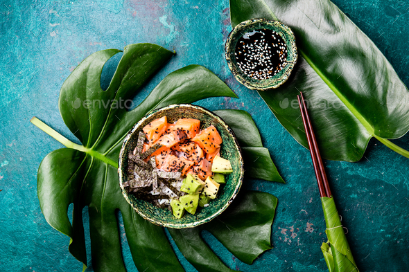 Hawaiian salmon poke poce with avocado, rice and sesamo served in bowls on tropical leaves - Stock Photo - Images