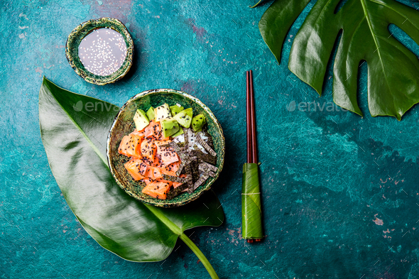 Hawaiian salmon poke poce with avocado, rice and sesamo served in bowls on tropical leaves - Stock Photo - Images