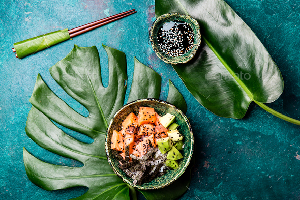 Hawaiian salmon poke poce with avocado, rice and sesamo served in bowls on tropical leaves - Stock Photo - Images