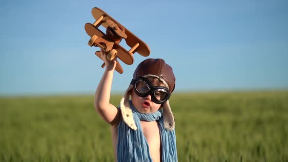 Happy child playing with vintage wooden airplane against blue sky background
