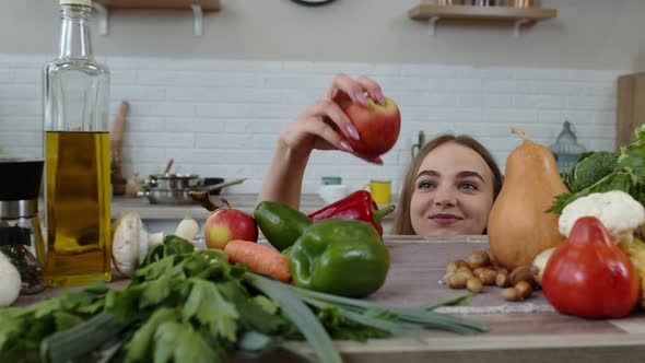 Girl Peeping From Under the Table and Stealing Fresh Apple and Eating It. Weight Loss, Diet Concept alt