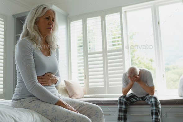 Front view of active senior Caucasian couple ignoring each other in bedroom at home