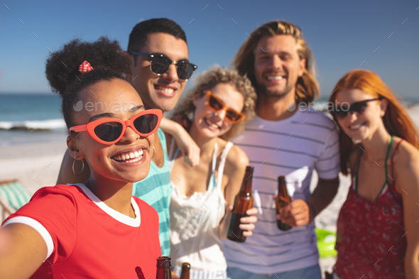 Front view of group of young diverse friends having fun together on the beach