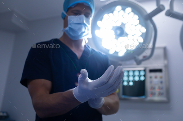 Low angle view of Caucasian male surgeon wearing surgical gloves in operation theater of hospital