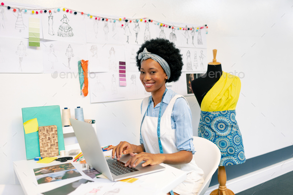 Side view of African american female graphic designer using laptop in office