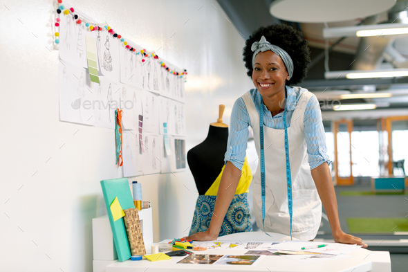 Front view of happy African american female graphic designer leaning on table in office