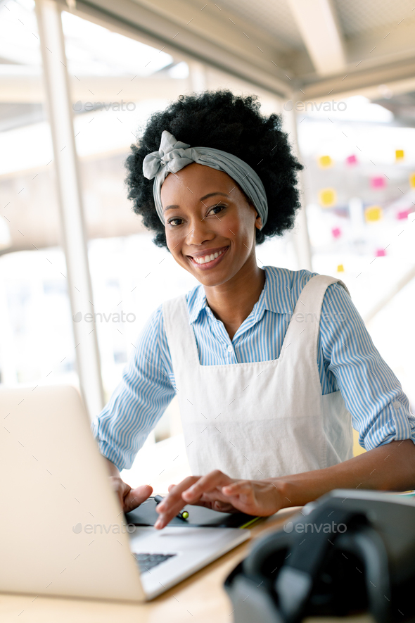 Front view of African american female graphic designer working on laptop at desk in office