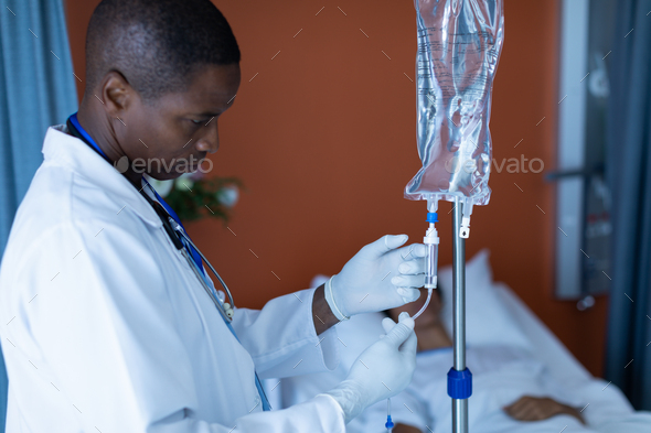 African-american male doctor injecting injection to female patients intravenous drip in the ward