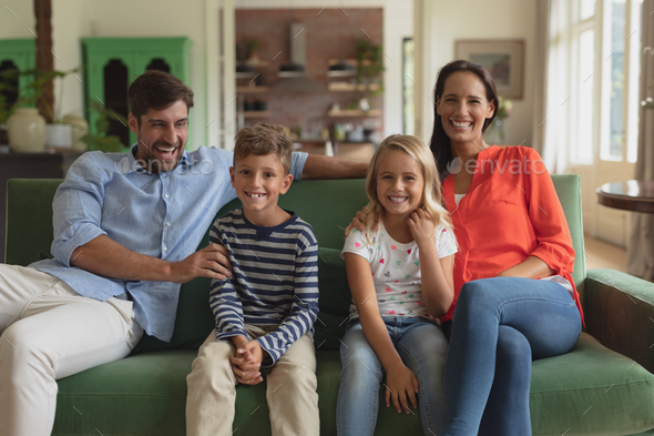 Front view of happy Caucasian family sitting together on sofa in living room art home