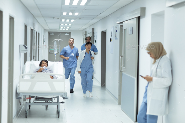 Front view of diverse medical team running in the corridor at hospital