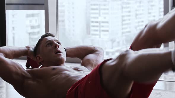 Muscular Man Lying on the Floor and Doing an Exercise for the Lower Abs Muscles alt