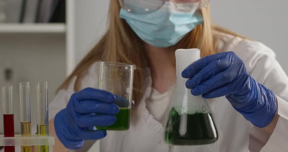 Close-up Shot. A Lab Worker Is Mixing Components in a Flask and Observing Their Reaction alt