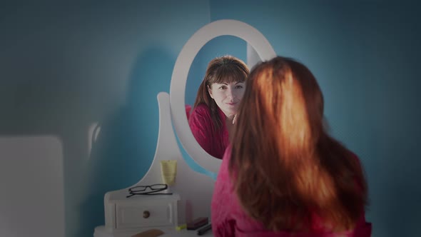 Pretty Brunette Woman Admires Herself in the Mirror and Smiles alt