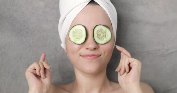 Portrait of a Young Beautiful Positive Funny Woman with a Towel on Her Head and Slices of Cucumber
