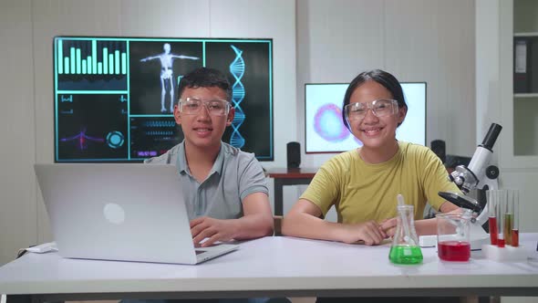 Young Asian Boy And Girl Smiling To Camera. Study With Scientific Equipment. Education Concept alt