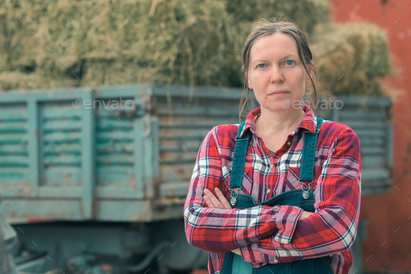 Female farmer posing in front of hay wagon