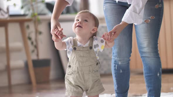 Baby Boy Taking First Steps with Mom's Help Learning to Walk at Home alt