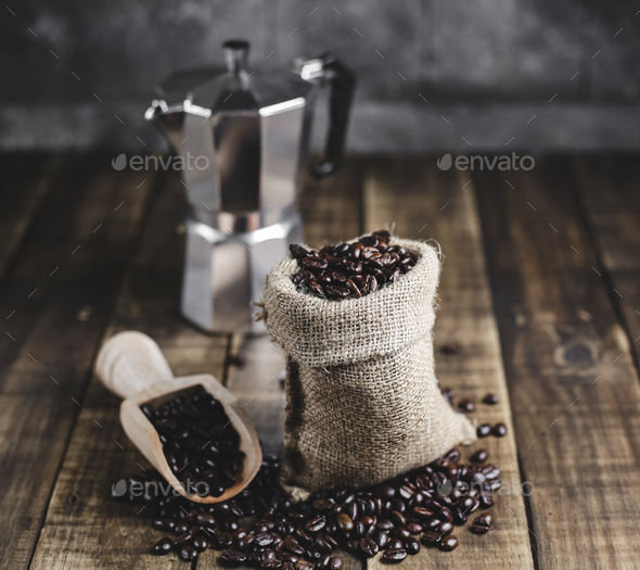 coffee beans in wooden scoop and moka pot with wood background