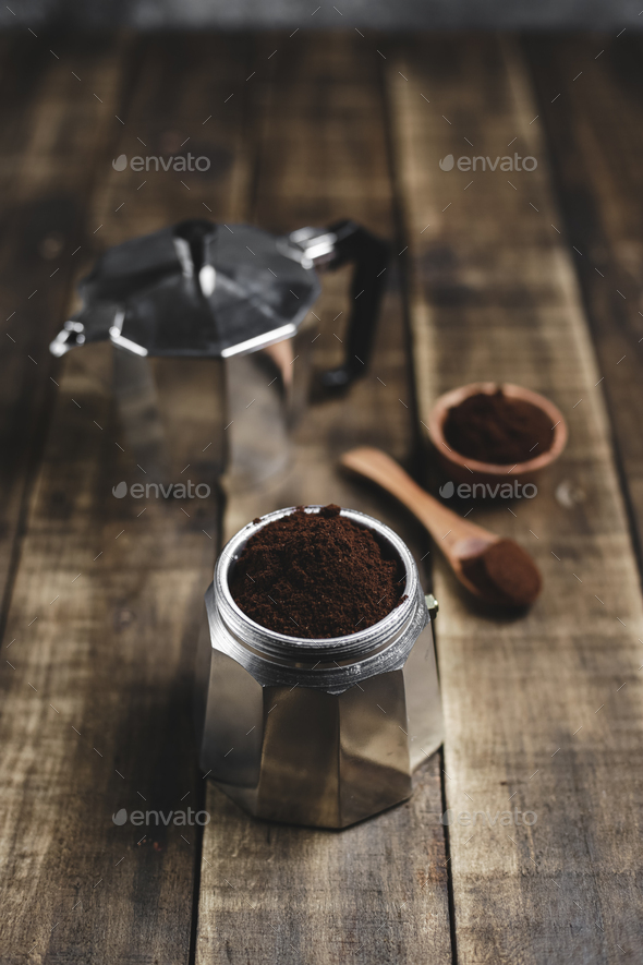 ground coffee and moka pot on wood background