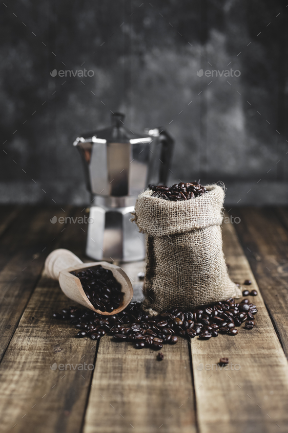 coffee beans in wooden scoop and moka pot with wood background