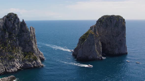 Yachts Boating around the Faraglioni Sea Stack Rock Formations in Italy alt