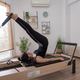 Young woman exercising on pilates reformer bed Stock Photo by