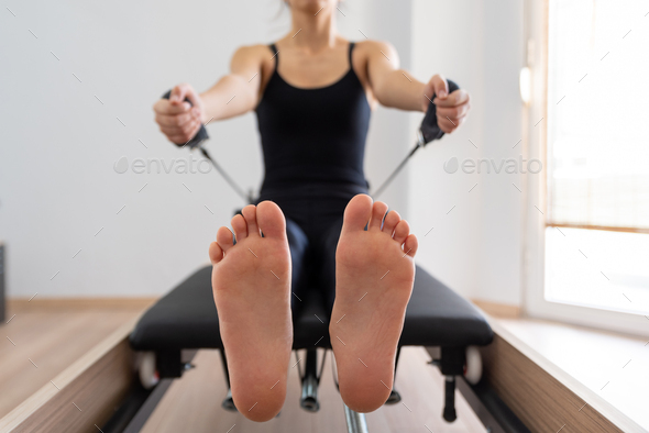 Young woman exercising on pilates reformer bed, feet close up Stock Photo  by sianstock
