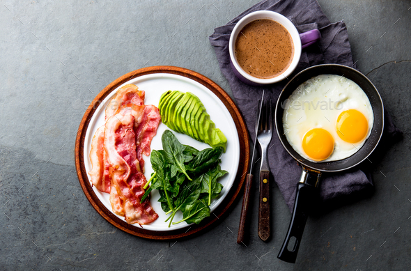 Ketogenic diet breakfast. fried egg, bacon and avocado, spinach and bulletproof coffee.