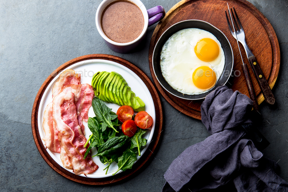 Ketogenic diet breakfast. fried egg, bacon and avocado, spinach and bulletproof coffee.